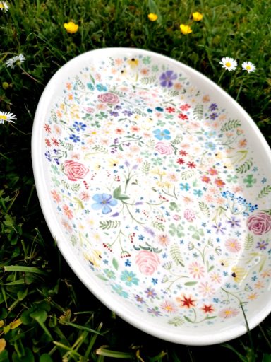 Schale mit buntem Blumenmuster auf grünem Gras.